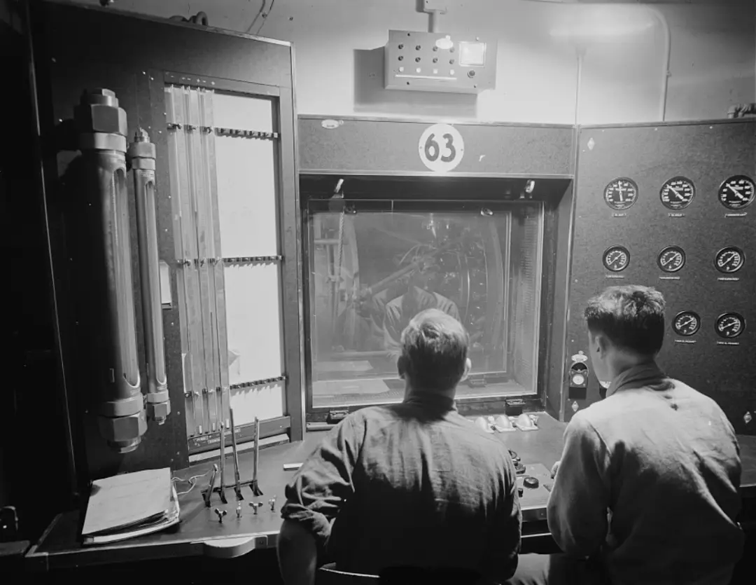  Engineers working at the control panel of a test stand at a large Eastern plant study the performance of a new Pratt and Whitney airplane motor.