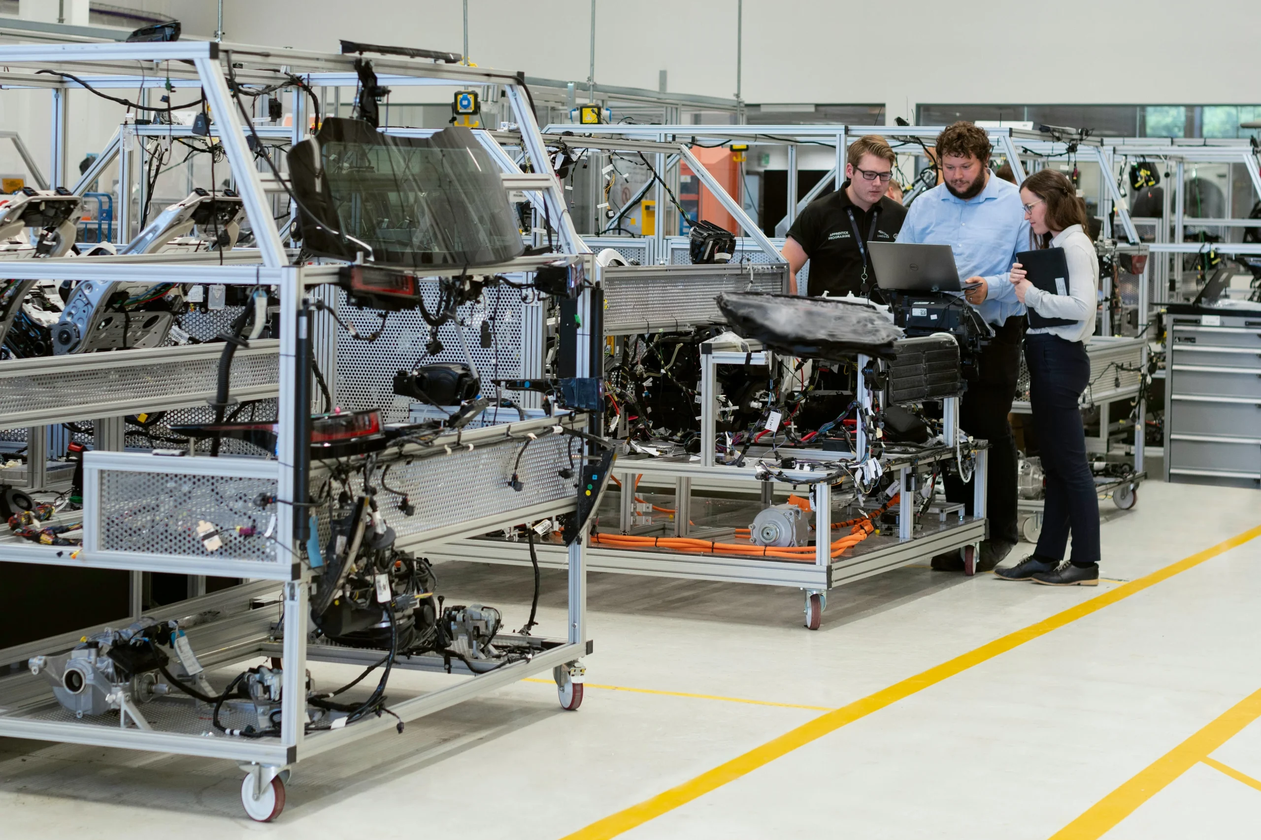 Automotive Maintenance Three people standing around a laptop in an automotive maintenance plant